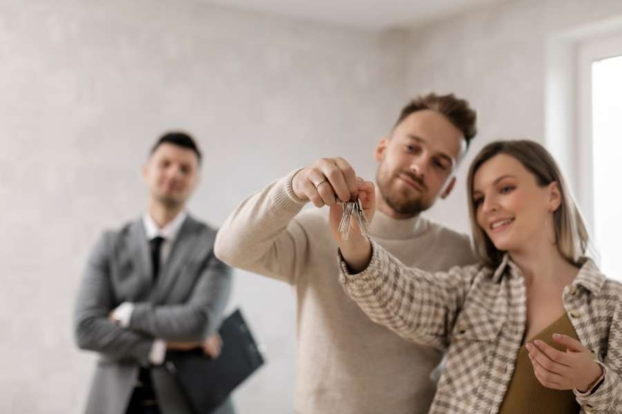 Un couple heureux reçoit les clés de son nouvel appartement des mains d'un agent immobilier, sans se douter des risques liés à un locataire indélicat.