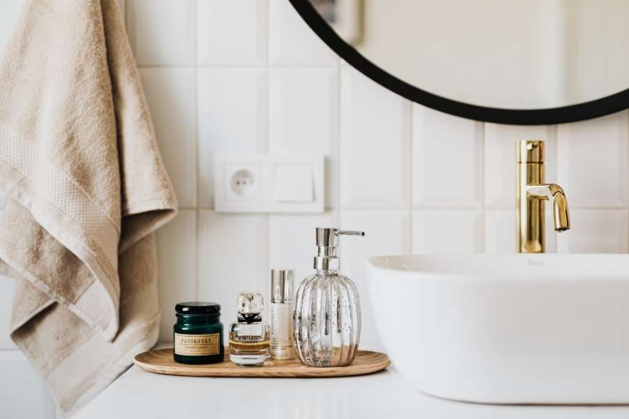 Plateau en bois avec cosmétiques et distributeur de savon dans une salle de bain organisée.